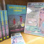 photo of several copies of the book Spectacular Things by Beck Dorey-Stein, alongside promotional material including bookmarks and a flyer.
