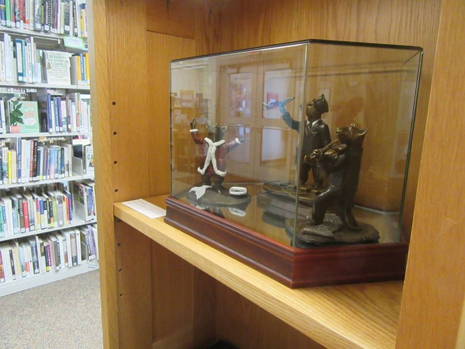 photo of three small bronze sculptures of storybook mice in a glass case