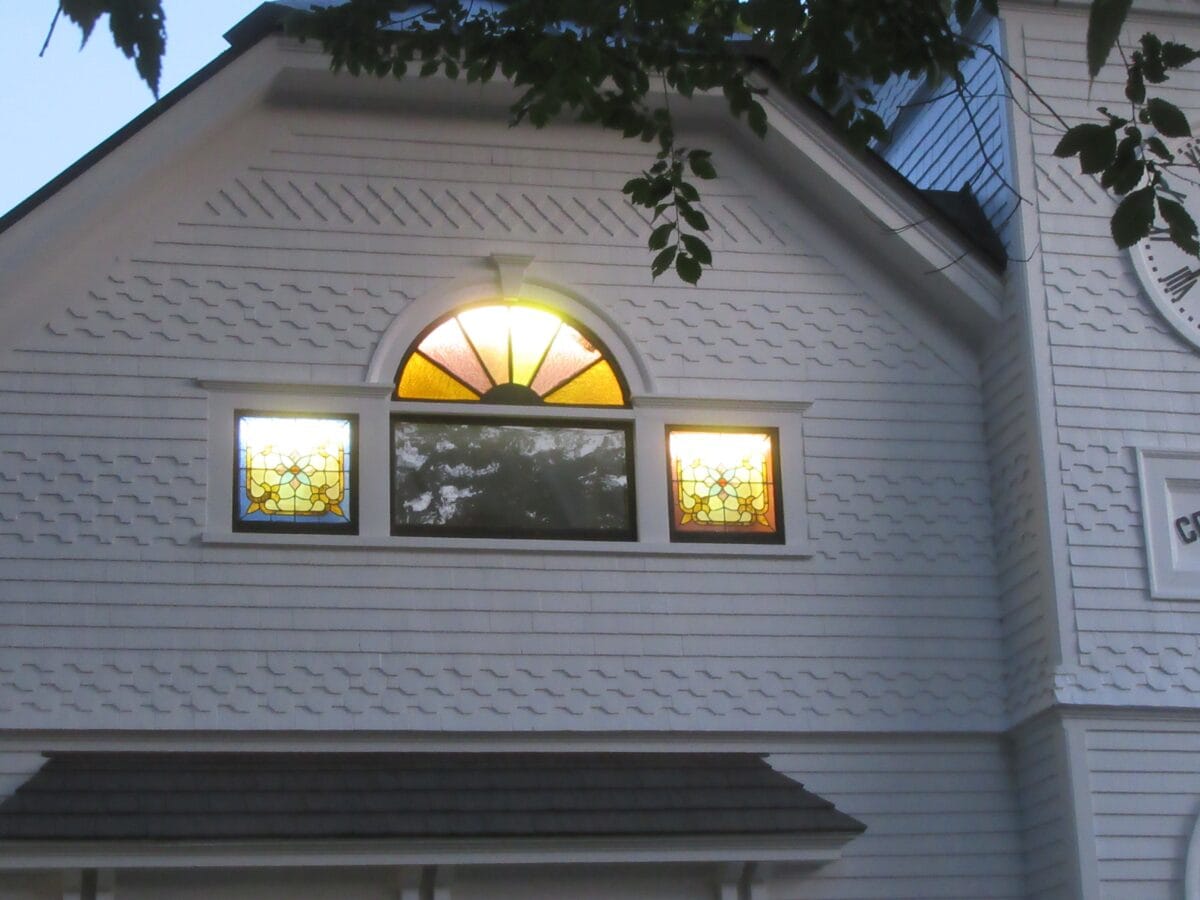 Photo of the exterior of the Cook Memorial Library at dusk showing lighted stained glass windows