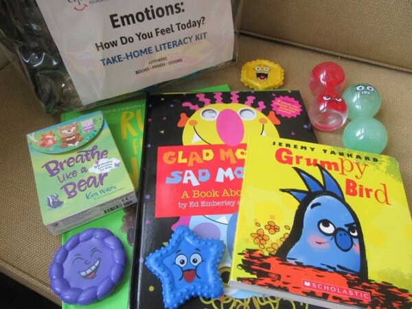 Photo of the books, toys, and a clear backpack, parts of an early literacy kit
