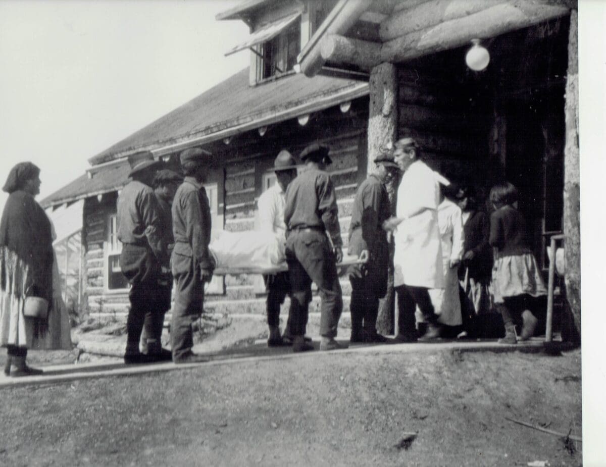 Photo taken in early 20th century of Fort Yukon Hospital in northern Alaska showing Grafton Burke greeting patients