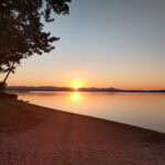 Photo of a sunrise over a lake with a beach in the foreground