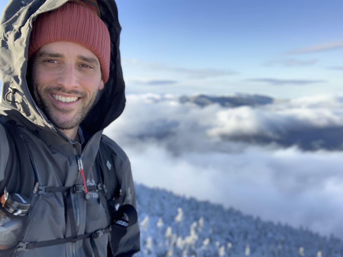 Photo of Michael Whittemore in a parka with a high summit background