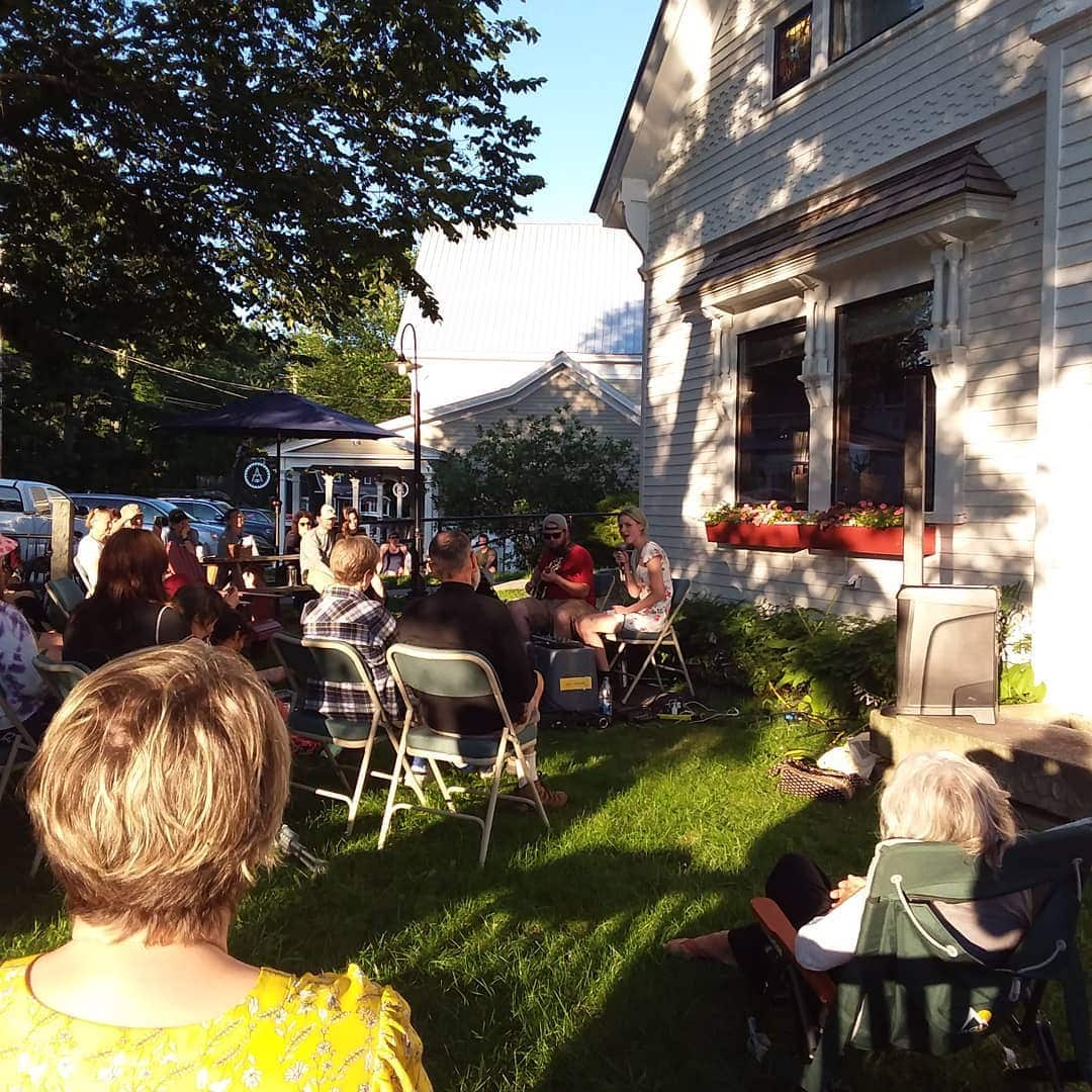A photo of musicians performing and audience enjoying in front of the Cook Memorial Library