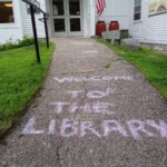 photo of the library walkway with the words "welcome to the library" written on it in chalk